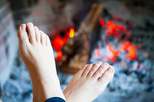 Feet are heated in the fire place — Stock Photo, Image