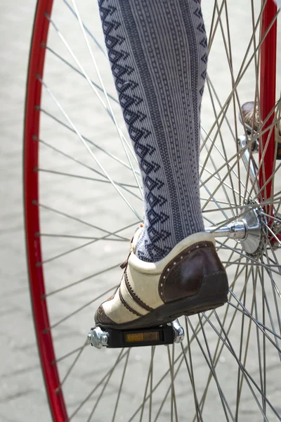 Close up of a velocipede wheel with the fragment of a cyclist's leg in beautiful oldfashioned wear — Stock Photo, Image