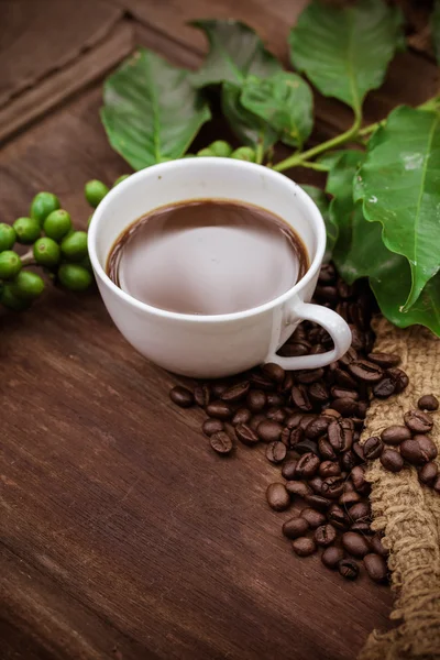 Kopp kaffe och bönor på trä bakgrund — Stockfoto