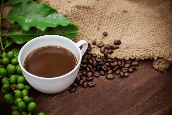 Kop koffie en bonen op hout achtergrond — Stockfoto