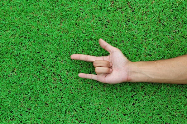 Mänsklig hand peka med fingret på grönt gräs bakgrundsstruktur — Stockfoto