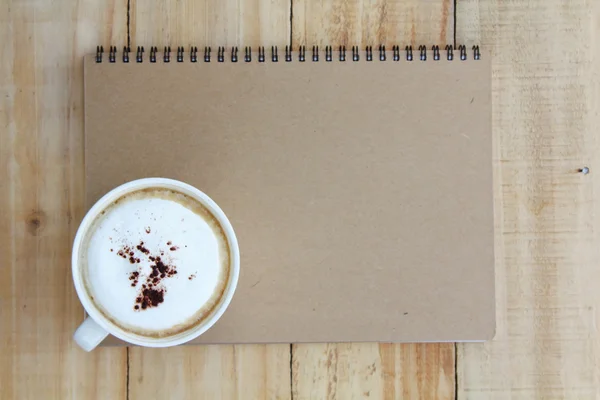 Cup of coffee and notebook paper on a wooden table — Stock Photo, Image