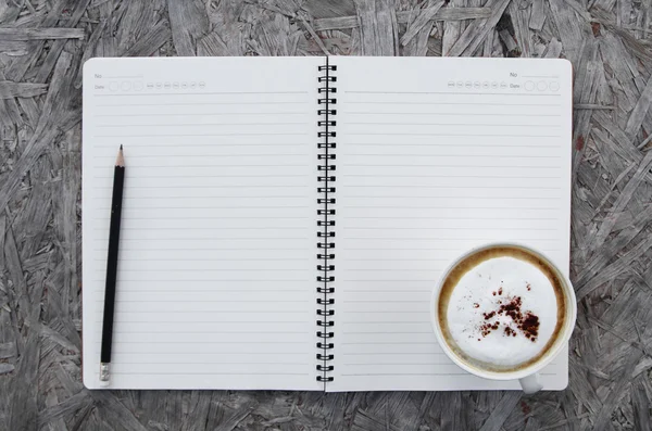 Cup of coffee and notebook paper on a wooden table — Stock Photo, Image