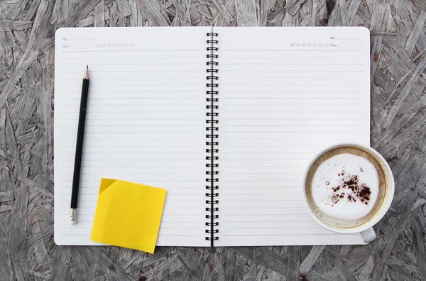 Cup of coffee and notebook paper on a wooden table — Stock Photo, Image