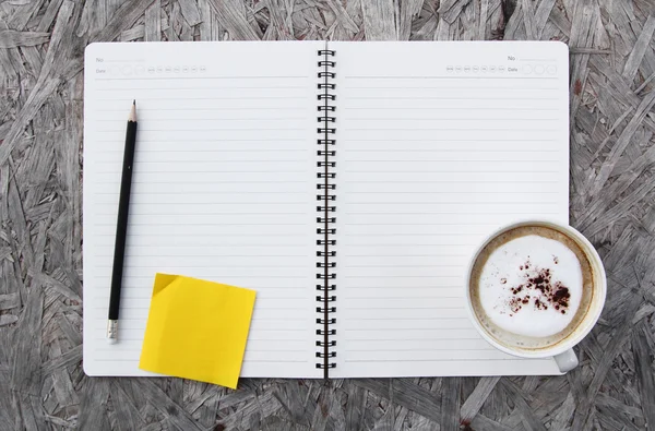 Kopje koffie en notebook papier op een houten tafel — Stockfoto