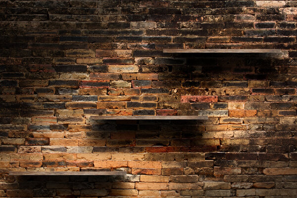 Empty wood shelves on old brick wall background, grunge industrial interior Uneven diffuse lighting version.