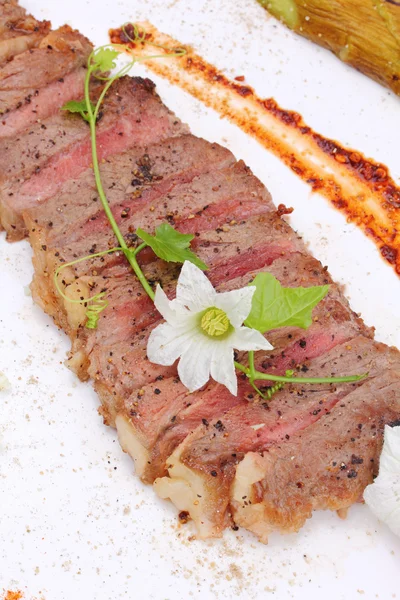 Beefsteak decorated with edible flowers — Stock Photo, Image