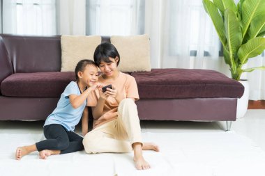Mutlu Asyalı kız ve kız kardeşi evde akıllı telefonda oynuyorlar.