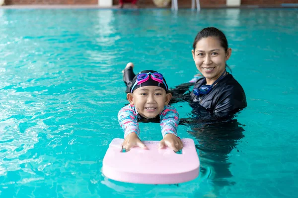 Girl learning to swim with coach at the leisure center