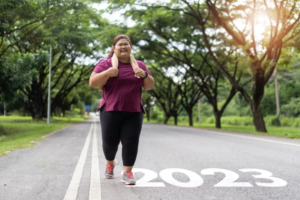 新的2023年或开始新的概念 写在柏油路上的2023字和亚洲胖女人准备跑步减肥 — 图库照片