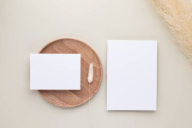 Boş kağıt kartlar, ahşap tabakta pampa otlu maket, bej arka plan, en az bej iş yeri kompozisyonu, düz yatak, maket