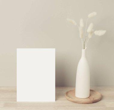 Ev dekorasyonu, masa üzerinde otlar, ön manzara, boş kağıt kart, tebrik kartı maketi. Ahşap arka planda vazodaki güzel beyaz pampalar