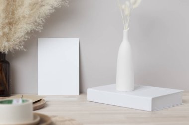 Boş kağıt kart, tebrik kartı maketi. Kurumuş Tavşan Kuyruğu ve otla dekorasyon, ön manzara, vazoda Güzel Tavşan Kuyruğu çimeni ve ahşap masa üzerinde beyaz kitap ve bej beton arka plan