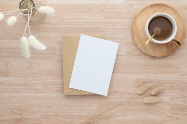 Boş kağıt kartlar, boş tebrik kartı davetiyesi vazoda kurutulmuş tavşan kuyruğu çimeni ahşap masa üzerinde kahve fincanı, ahşap masa arkaplanı, minimum ahşap masa çalışma alanı kompozisyonu, düz yatak, model.