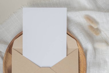 Boş kağıt kartlar, boş tebrik kartı davetiyesi, el işi zarflı maket, masa arkasında kurutulmuş tavşan kuyruğu çimeni, minimum masa çalışması kompozisyonu, düz yatak, model.