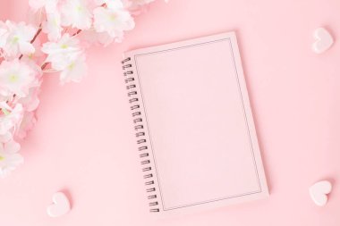 Pembe arka planda çiçek olan pembe bir defter.