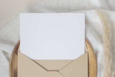 Boş kağıt kartlar, boş tebrik kartı davetiyesi, el işi zarflı maket, masa arkasında kurutulmuş tavşan kuyruğu çimeni, minimum masa çalışması kompozisyonu, düz yatak, model.