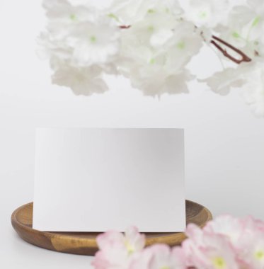 Tebrik kartı maketi. Beyaz çiçekli dekorasyon, ön manzara, tahta tabakta boş kağıt kart ve beyaz arkaplan