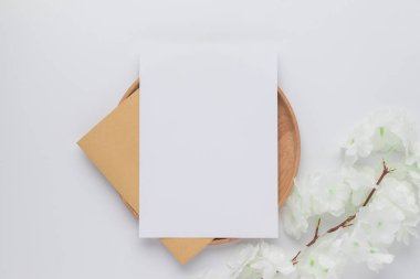 Boş tebrik kartı daveti. Kahverengi zarfın üzerinde kurumuş tavşan kuyruğu, beyaz arka planda çimen, minimum masa çalışma alanı kompozisyonu, düz yatak, maket.