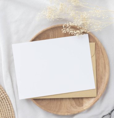 Boş tebrik kartı daveti. Kahverengi zarf üzerinde Mockup 5x7. Bej arka planda kurumuş çiçekler.