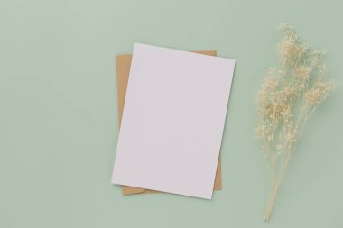 Boş tebrik kartı daveti Kahverengi zarf üzerinde Mockup 5x7 pastel yeşil arka plan, düz yatış, model