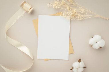 Boş tebrik kartı daveti. Kahverengi zarf üzerinde Mockup 5x7. Bej arka planda kurumuş çiçekler.