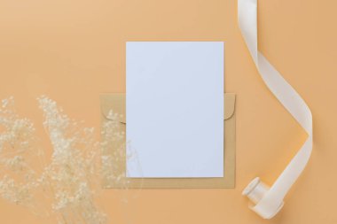 Boş tebrik kartı daveti Kuru çiçekli zarfa Mockup 5x7 Ve kağıt zemin üzerinde kurdele, düz uzanma, taklit
