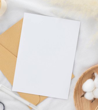 Boş tebrik kartı daveti Kuru çiçekli zarf üzerinde Mockup 5x7 ve beyaz kumaş arka planda kurdele, düz yatış, model