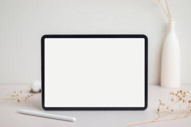Tablet empty white screen with pencil mock-up. Cotton flower and dry leaves on beige background mockup for design