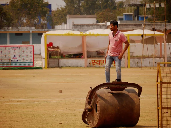 2022 Mart 'ında Hindistan' da Katni Madhya Pradesh şehrinde, kriket sahasında demir silindirin üzerinde duran Asyalı bir çocuk..