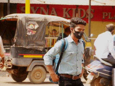 Hindistan 'ın Katni Madhya Pradesh şehrinin arka planında 2022 Mart' ında kimliği belirsiz Hintli çocuk şehir trafiğinde yol ayrımında maske takıyor..