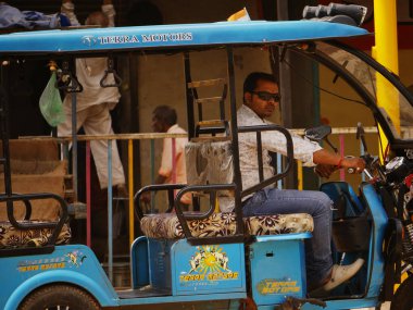Indian city auto rickshaw driver wearing sunglasses waiting for passengers at road side at city Katni Madhya Pradesh in India on March 2022.