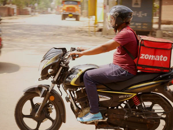 ゾマト宅配会社の現場幹部が重い食品容器を背負ったバイクに乗って 2022年3月にインドのカッニ マディヤ プラデシュ州で道路コンセプトの配達少年 — ストック写真