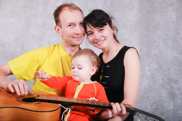 Jovens pais felizes e pequeno bebê com guitarra — Fotografia de Stock