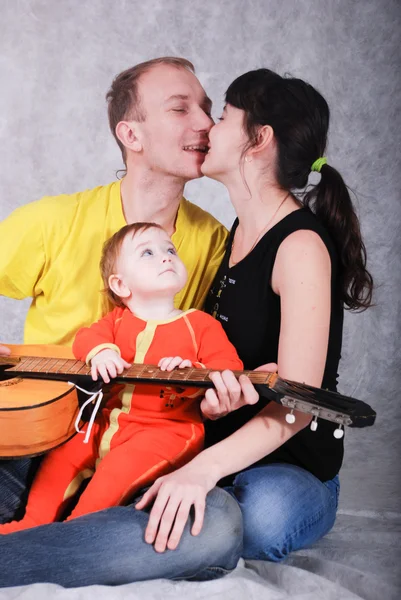 Giovani genitori felici e piccolo bambino con la chitarra — Foto Stock