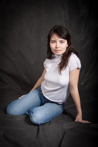 Женщина в джинсах сидит на полу — стоковое фото