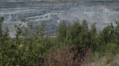 Asbest ocağı, açık çukurda çalışan bir çöp kamyonu. Çöp kamyonları, maden endüstrisi, maden kamyonları, yük treni. Açık maden ocağının havadan çekilmiş videosu. Bir sürü makine çalışıyor..