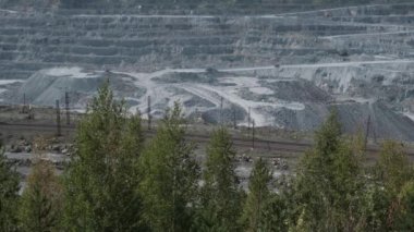 Asbest ocağı, açık çukurda çalışan bir çöp kamyonu. Çöp kamyonları, maden endüstrisi, maden kamyonları, yük treni. Açık maden ocağının havadan çekilmiş videosu. Bir sürü makine çalışıyor..