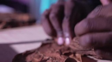 Afrikalı, elleriyle bir yapraktan puro içiyor.