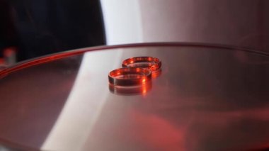 Nikah yüzükleri yakın. Yüzükler kırmızı ışıkta masanın üstünde..