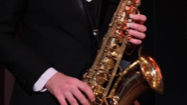  Siyah montlu bir adam saksafon çalıyor.