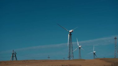 Güneşli bir günde mavi gökyüzü ve beyaz bulutlarla yakın çekim rüzgar türbinleri veya rüzgar enerjisi dönüştürücüsü