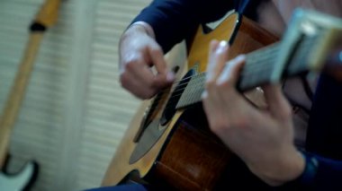 Erkek eller gitar çalıyor.