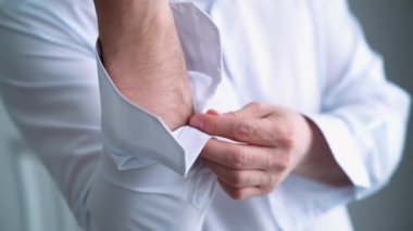  İş adamı giyiniyor. Beyaz gömlekli şık bir iş adamı kravatını düzeltiyor ve ceketini ilikliyor. Kapat