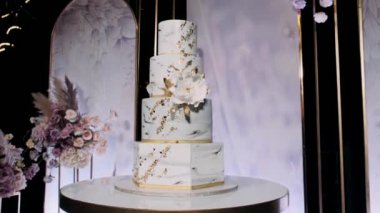 Dört kademe beyaz ve altın rengi pasta.