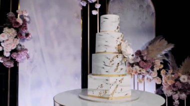 Dört kademe beyaz ve altın rengi pasta.