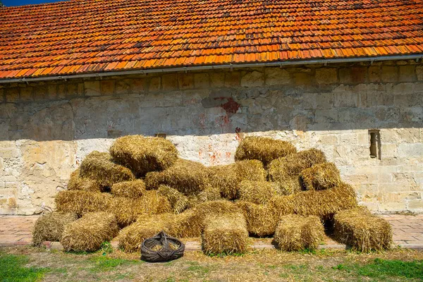 一座旧砖楼前的金色草堆 砖墙附近堆放干草 — 图库照片