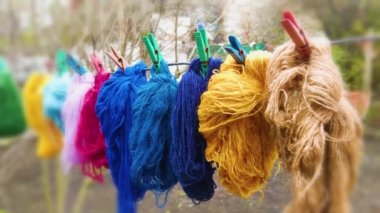 Yünlü renkli iplikler dışarıda çamaşır mandallarıyla bir çamaşır ipinde asılı.