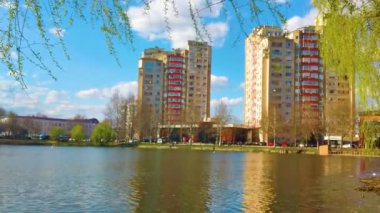 Beautiful green spring park. Tranquil landscape at a lake, with the vibrant sky, white clouds and the trees