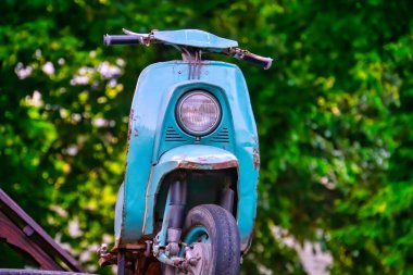 A vintage light blue scooter of retro style stands near an alley